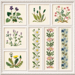 May include: A framed embroidery sampler with a collection of floral designs. The sampler showcases embroidered images of wildflowers, including violets and daisies, in green, purple, pink, and yellow threads on a cream-coloured background.