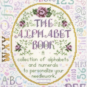 Könnte beinhalten: Ein Kreuzstich-Design mit dem Titel "The Alphabet Book". Das Design zeigt einen ovalen Rahmen mit floralen Akzenten und dem Titel in lila Buchstaben. Der Text darunter lautet "Eine Sammlung von Alphabeten und Zahlen zur Personalisierung Ihrer Handarbeiten."
