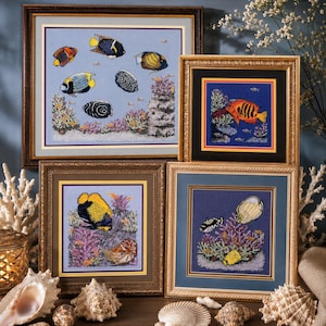 May include: Several framed needlepoint artworks depicting colorful fish and coral reefs. The artworks feature various fish species in vibrant colors, set against a blue background. The frames are ornate, with gold and brown tones, and the artworks are displayed with seashells.