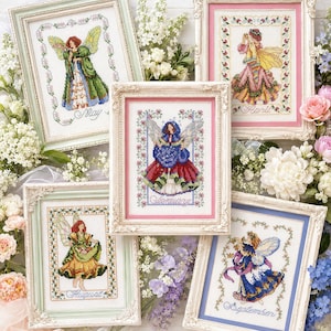 Könnte beinhalten: Fünf gerahmte Kreuzstich-Kunstwerke mit Feen, die verschiedene Monate darstellen. Jede Fee ist in einem detaillierten, farbenfrohen Design mit floralen Bordüren und dem Namen des Monats dargestellt. Die Rahmen haben verzierte, weiße und pastellfarbene Ränder.
