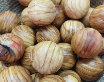 May include: A collection of wooden spheres with a natural wood grain pattern. The spheres are various shades of light and dark brown, and are contained in a woven basket. The spheres appear to be smooth and round.