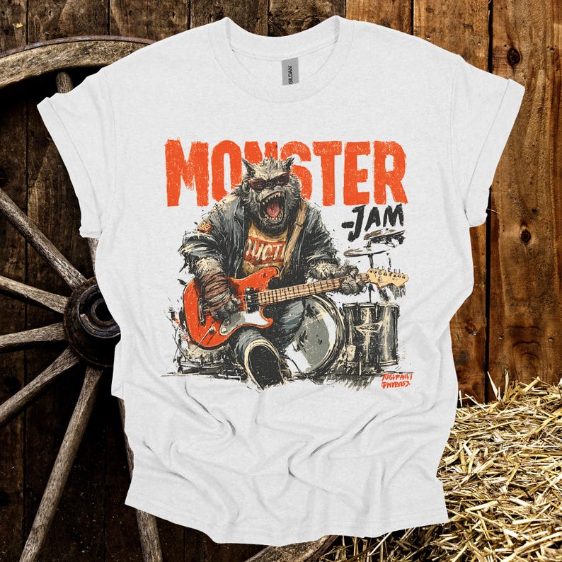 May include: White t-shirt with the words "MONSTER JAM" in orange, featuring a monster playing a red guitar and drums. The graphic has a distressed, vintage look.