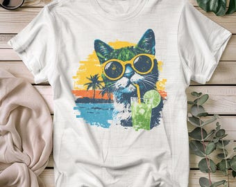 May include: White t-shirt with a graphic of a cat wearing sunglasses and drinking a green cocktail with a lime slice. The cat is set against a tropical sunset backdrop with palm trees and ocean waves. The shirt is made of a soft, comfortable material.