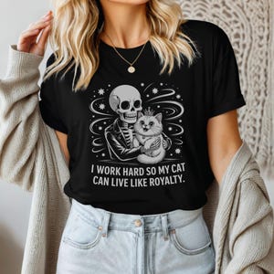 Funny Skeleton Cat Lover T-Shirt - “I Work Hard So My Cat Can Live Like Royalty” - Gothic Pet Humor Tee, Gift for Cat Owners, Unisex Shirt