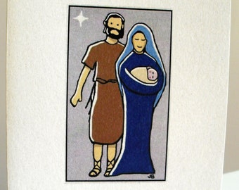 Op de afbeelding: Een kerstkaart met een eenvoudige illustratie van de Heilige Familie. De kaart is wit met een lichtgrijze achtergrond voor de illustratie. De illustratie toont een man in een bruine gewaden en een vrouw in een blauwe gewaden die een baby vasthoudt. De tekst "VREDE" is onder de illustratie gedrukt.