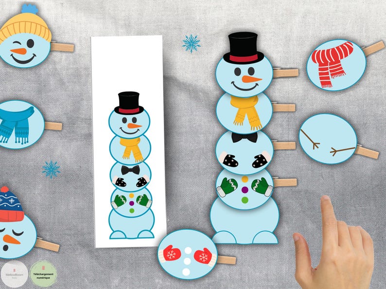 Op de afbeelding: Een winterthema knutselproject met sneeuwman uitsparingen en accessoires zoals hoeden, sjaals en wanten. De uitsparingen zijn bevestigd aan wasknijpers, wat duidt op een doe-het-zelf activiteit voor kinderen of feestelijke decoraties.