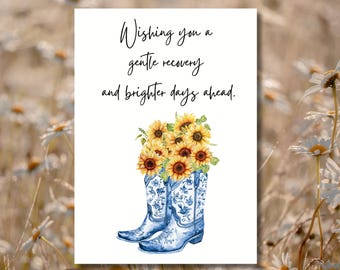 May include: A greeting card with a watercolor illustration. The card features a pair of blue cowboy boots filled with sunflowers. The text reads, "Wishing you a gentle recovery and brighter days ahead."