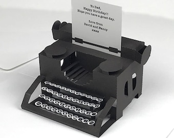 May include: A black papercraft typewriter with white keys and a card that reads "To Dad, Happy Birthday!! Hope you have a great day. Love from David and Nancy xxxx."