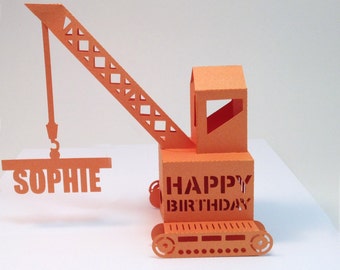 May include: Orange papercraft construction crane with a hook lifting a sign that says "Sophie". The base of the crane says "Happy Birthday".