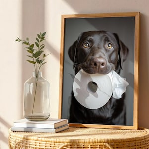 Puede incluir: Impresi&oacute;n enmarcada de un Labrador Retriever color chocolate sosteniendo un rollo de papel higi&eacute;nico blanco en la boca. El perro tiene una expresi&oacute;n concentrada. La impresi&oacute;n est&aacute; en un marco de madera.