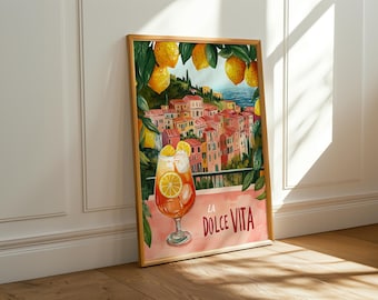 May include: A framed watercolor print featuring a vibrant Italian coastal scene with colorful buildings and a refreshing drink. The print includes the text "LA DOLCE VITA" and is surrounded by lemons and greenery, evoking a sense of summer and relaxation.