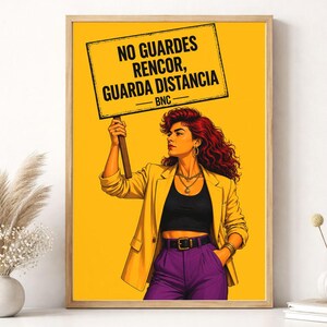 Puede incluir: Arte mural imprimible con una mujer sosteniendo un cartel con texto en español. Lleva una blazer amarilla, un top negro y pantalones morados. El fondo es amarillo y la obra está enmarcada en madera.