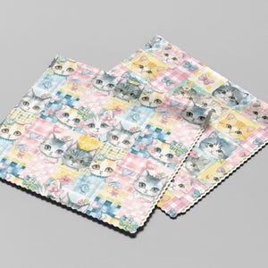 May include: Two square microfiber cloths featuring a repeating pattern of illustrated cat faces in shades of pink, blue, and yellow. The design includes small butterflies and flowers interspersed among the cats, with scalloped, pinked edges.