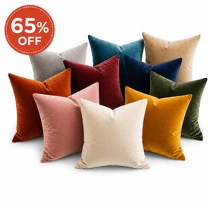 May include: A collection of plush velvet throw pillows in various colors, including teal, navy, gold, and burgundy. The pillows are arranged in a group, with a round red sticker that says "65% OFF" in white text.