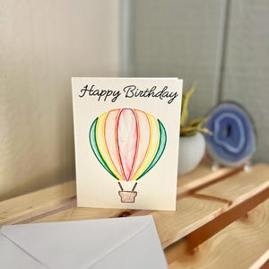 Cartão de aniversário de balão de ar quente, cartão de feliz aniversário em aquarela, cartão de felicitações para aniversário infantil, cartão em branco, balão de ar quente em aquarela