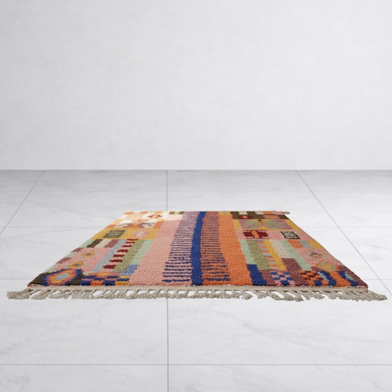 K&ouml;nnte beinhalten: Ein rechteckiger Teppich mit einem farbenfrohen, geometrischen Design. Der Teppich zeigt vertikale Streifen in Rosa, Orange, Blau und Gr&uuml;n mit einem Fransenrand an der Unterkante. Der Teppich ist ca. 122 cm x 183 cm gro&szlig;.