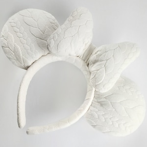 May include: White headband with a large white bow and two large white ears. The ears and bow have a textured, knitted pattern.