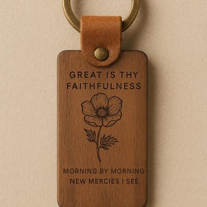 Könnte beinhalten: Ein Holzschlüsselanhänger mit einem braunen Lederband und einem Metallring. Der Schlüsselanhänger zeigt ein florales Design und den Text "Great is thy faithfulness, morning by morning new mercies I see."