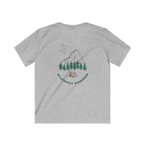 May include: A heather gray t-shirt featuring a mountain and forest graphic with a tent, moon, and the text "Wilderness Wanderer". The design is in green and brown tones.