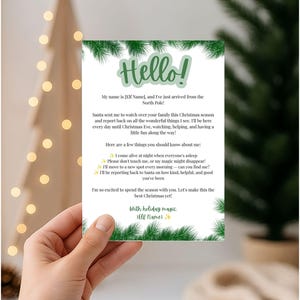 May include: A rectangular white card featuring green pine branch borders and the text Hello! My name is [Elf Name], and I've just arrived from the North Pole! Santa sent me to watch over your family this Christmas season and report back.