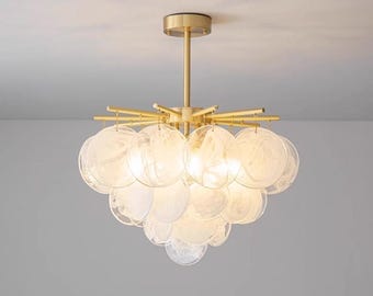 May include: A modern ceiling light fixture with a gold finish and a cluster of round, translucent glass shades. The light is suspended from a central rod and features multiple arms extending outwards, holding the glass shades.
