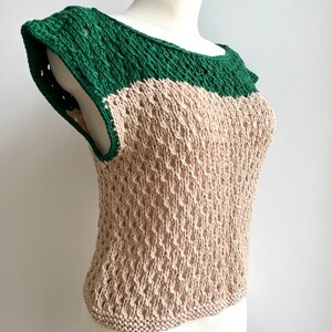 Puede incluir: Una blusa sin mangas de dos tonos con un dise&ntilde;o de tejido abierto. El cuello y los hombros son verdes, mientras que el cuerpo es beige. La tela de punto tiene un patr&oacute;n texturizado y abierto. La blusa se muestra en un maniqu&iacute;.