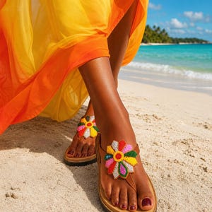 May include: Brown leather sandals with a colorful beaded flower design. The sandals have a cork sole and are worn on a sandy beach. The person is wearing a flowing yellow and orange dress.