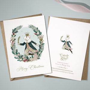 A Christmas card featuring a watercolour illustration of The Mouse King holding a sword and wearing a crown. The mouse is surrounded by a wreath of holly, berries, and candy canes. The card reads "Merry Christmas".