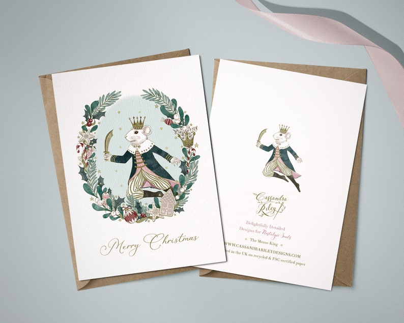 A Christmas card featuring a watercolour illustration of The Mouse King holding a sword and wearing a crown. The mouse is surrounded by a wreath of holly, berries, and candy canes. The card reads "Merry Christmas".