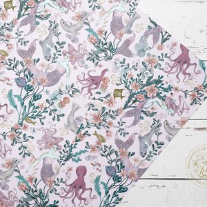 A wrapping paper featuring mermaids, octopuses, and seals in a whimsical underwater scene. The pattern is set against a light pink background with delicate floral accents and bubbles.