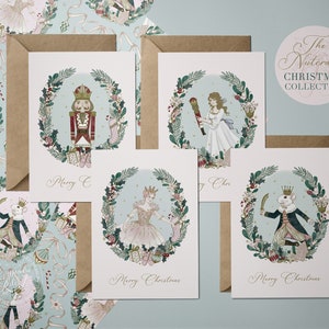 Set of four illustrated Christmas cards featuring characters from The Nutcracker. Each card features a different character in a wreath of greenery with the text "Merry Christmas".