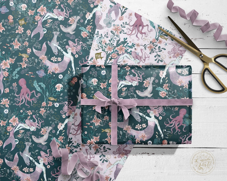 Teal and pink wrapping paper featuring a mermaid, seal and octopus design. The paper is wrapped around a gift box with a pink ribbon.