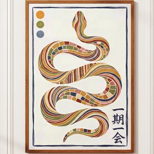 以下が含まれることがあります： 額縁に入った、ヘビのイラストが描かれたアートプリント。ヘビは、茶色、オレンジ、緑の色合いで、カラフルで模様のある鱗で描かれています。アートワークには日本語のテキストと3つの色のドットが含まれています。