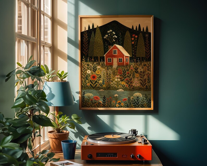 May include: A framed art print depicts a red house nestled in a field of flowers and trees, with a mountain in the background. A vintage orange record player sits on a wooden surface below the artwork, next to a blue lamp and potted plants.