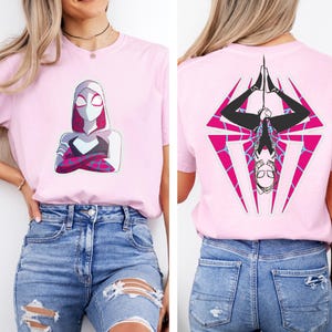 Puede incluir: Camiseta rosa claro con un gr&aacute;fico de superh&eacute;roe en la parte delantera y trasera. El gr&aacute;fico frontal muestra al personaje con los brazos cruzados. El gr&aacute;fico trasero muestra al personaje colgado boca abajo dentro de un rombo rosa y negro.