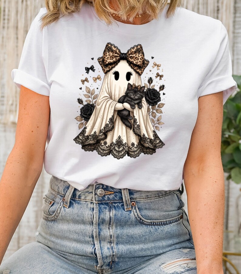 Pu&ograve; includere: Una t-shirt bianca a maniche corte con la grafica di un fantasma che indossa un fiocco leopardato e tiene in braccio un gatto nero. Il fantasma &egrave; decorato con un bordo in pizzo nero sull'orlo, circondato da rose nere e piccoli fiocchi.