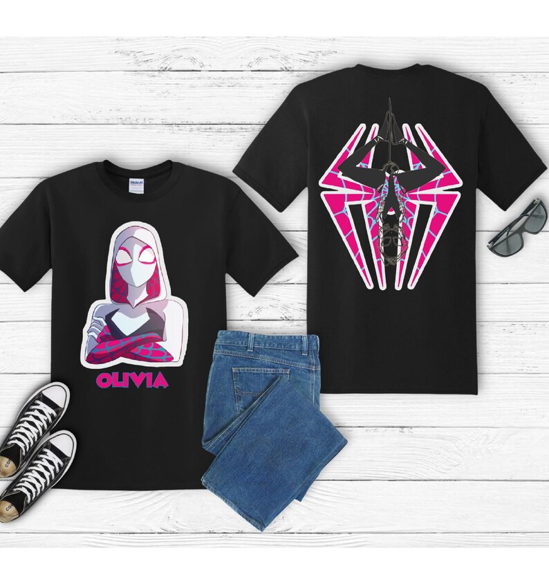 Puede incluir: Camisetas negras con dise&ntilde;os gr&aacute;ficos. Una camiseta presenta un personaje con una m&aacute;scara blanca y rosa y el nombre "OLIVIA". La otra camiseta muestra un dise&ntilde;o de telara&ntilde;a rosa y blanca. Incluye vaqueros azules y zapatillas negras.