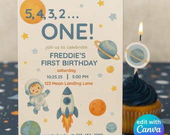 Könnte beinhalten: Eine Geburtstagseinladung mit Weltraumthema mit dem Text "ONE!" und "FREDDIE'S FIRST BIRTHDAY." Das Design umfasst Planeten, Sterne, eine Rakete und einen Astronauten. Ein Cupcake mit einer Kerze zum Thema Planet befindet sich im Vordergrund.