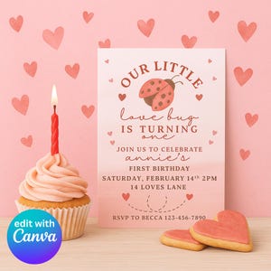 May include: A pink birthday invitation with the text "Our Little Love Bug is Turning One." The invitation includes a ladybug graphic and heart accents. A cupcake with a lit red candle and heart-shaped cookies are in the foreground.
