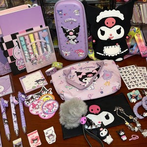 May include: A collection of Kuromi-themed stationery and accessories in shades of purple, pink, and black. Items include pens, stickers, a pencil case, a tote bag, notebooks, bracelets, and a plush figure. The items are arranged on a wooden surface.