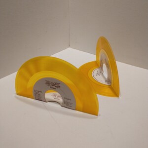Small, shiny, round 45 size, vinyl records are bent on the bottom to make bookends. The color of the album is yellow.