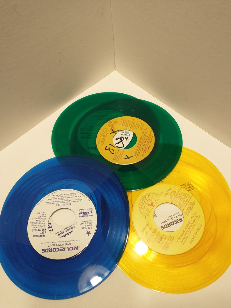Small, shiny, round 45 size, vinyl records are displayed. The color of the album is blue, green, and yellow.