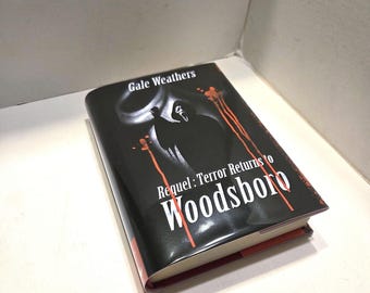May include: A hardcover book titled "Requel: Terror Returns to Woodsboro" by Gale Weathers. The book has a black cover with a white graphic and red accents. The book is resting on a white surface.