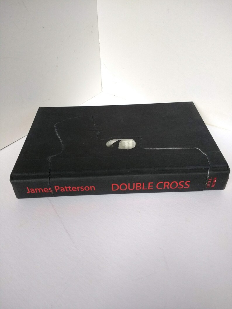 May include: A black hardcover book with the title "DOUBLE CROSS" in red text and the author "James Patterson" in red text. The book is published by Little, Brown.