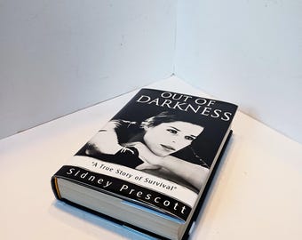 May include: A hardcover book titled "Out of Darkness" by Sidney Prescott. The book cover features a black and white image of a woman's face. The text "A True Story of Survival" is also on the cover.