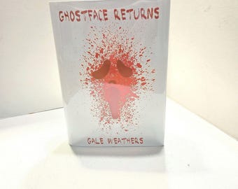 May include: A white rectangular product with the text "GHOSTFACE RETURNS" in red at the top and "GALE WEATHERS" at the bottom. A red and pink splatter design is in the center.