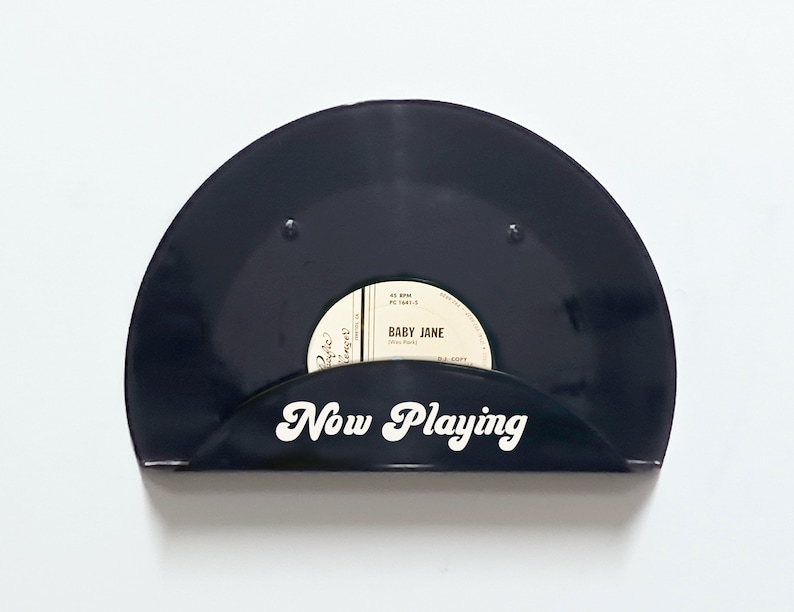 May include: Black vinyl record holder with the words "Now Playing" in white script. The holder displays a 45 RPM record with the label "Baby Jane". A stylish way to showcase your favorite vinyl.