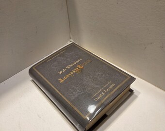 May include: A hardcover book titled "Leaves of Grass" by Walt Whitman. The book has a dark gray cover with gold lettering and a gold border. The book is a 150th Anniversary Edition, edited and with an afterword by David S. Reynolds.