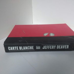 May include: A red and black hardcover book titled "Carte Blanche" by Jeffery Deaver, published by Simon & Schuster.