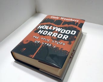 May include: A book titled "Hollywood Horror: The True Story of Stab 3" by Gale Weathers. The cover features a black and orange graphic design with the title in white.